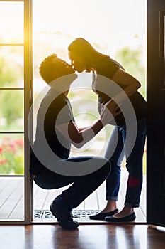 Mixed Race Pregnant Couple Kissing in Doorway.