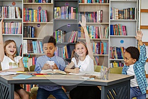 Mixed-race pupils study and write at table in library or classroom. Back to school