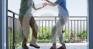 Mixed race senior couple dancing together in the balcony at home