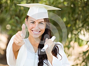 Mixed Race Teen Girl Gives Thumbs Up at Graduation In Cap and Gown