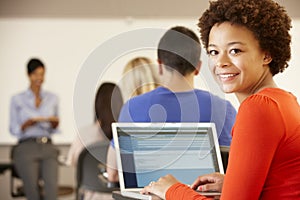 Mixed race teenage girl using laptop in class