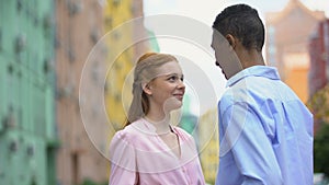 Mixed-race teenager tenderly stroking shoulder of girl saying compliments, date
