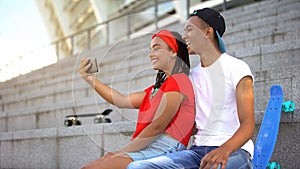 Mixed race teenagers taking selfie on smartphone for blog, trendy lifestyle