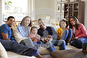 African American , three generation family sitting on sofa in the living room together, eating popcorn and looking to camera, clos