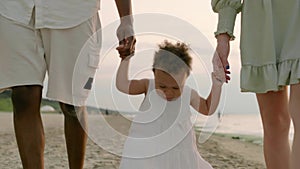 Mixed race toddler daughter walks with mother and father