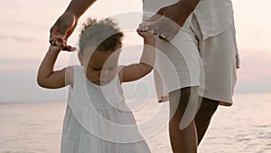 Mixed race toddler girl walks with Afro-American daddy