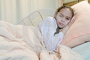 Mixed race tween girl in hospital bed, looking at camera