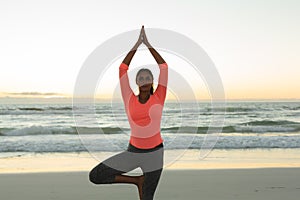 Mixed race woman on beach practicing yoga during sunset