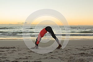 Mixed race woman on beach practicing yoga during sunset