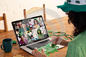 Mixed race woman in costume making st patrick's day video call to friends on laptop at home