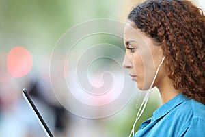 Mixed race woman e-learning using tablet and earphones