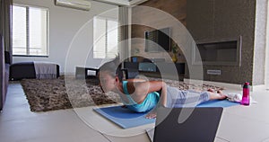 Mixed race woman excercising on a mat with laptop