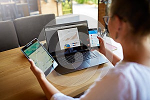 Mixed race woman in glasses working with multiple electronic internet devices. Freelancer businesswoman has tablet and