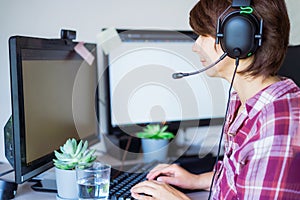 Mixed-race Woman in headset has video meeting or call. Customer service support representative works on a laptop