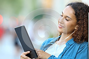 Mixed race woman listening music with a tablet