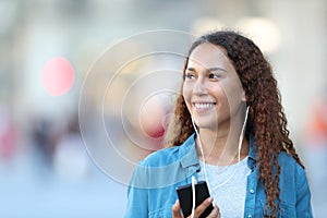 Mixed race woman listening to music looking at side