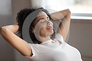 Mixed race woman putting hands behind head resting indoors