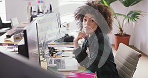 Mixed race woman tapping on computer in creative office