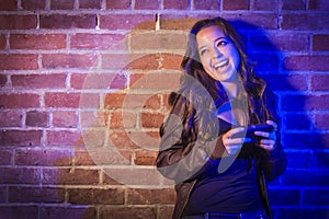 Mixed Race Woman Using Her Cell Phone Against Brick Wall