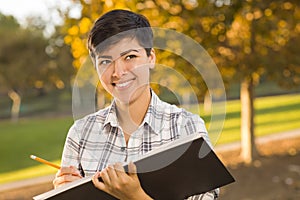 Mixed Race Young Female Holding Sketch Book and Pencil Outdoors