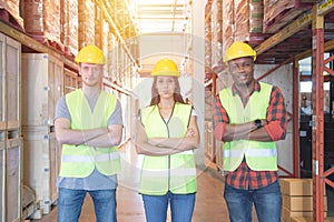 Mixed raced caucasian men and woman workers in safety hardhat and safety uniform standing with smile and posing in warehouse