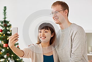 Mixed-raced couple taking selfie at christmas
