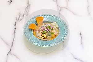 Mixed sea bass and prawn ceviche with marinated sweet potato and corn on a blue deep plate