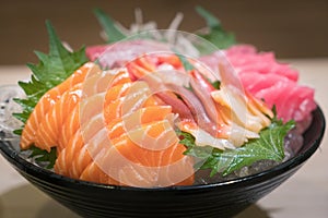 Mixed sliced fish sashimi on ice in black bowl. Sashimi Salmon Tuna Hamachi Prawn and Surf Calm set, raw fish, japanese food in