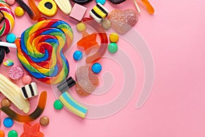 mixed sweets lollipops and candies over pink like festive background with copy space