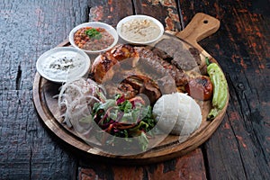 Mixed turkish kebab plate with rice, vegetables and dip sauces on rustic wooden background