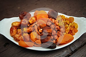 Mixed turkish nuts walnuts, raisins, dried apricots, almonds, hazelnuts. Assorted nuts and dried fruits in white plate.