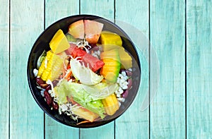 Mixed vegetable and fruit salad in black bowl