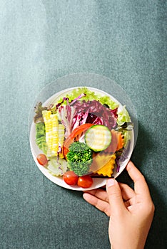 Mixed vegetables salad holding by hand