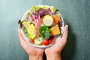Mixed vegetables salad on white dish holding by hand