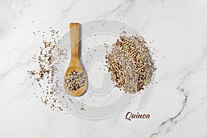 Mixed white, red and black quinoa grains on wooden spoon and pile scattered on marble table