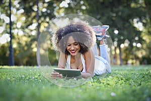 Mixed woman with afro hairstyle looking at her tablet computer