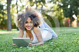 Mixed woman with afro hairstyle looking at her tablet computer