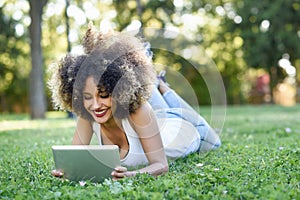 Mixed woman with afro hairstyle looking at her tablet computer