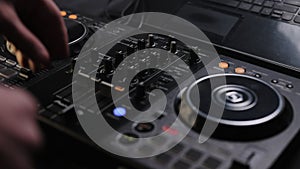 Mixer controller composing new mix on vinyl plate. DJ sound control console for mixing dance music in disco club. Hands