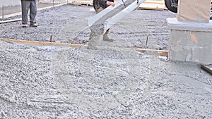 Mixer truck pouring ready mixed concrete for a driveway near house that is wet cement