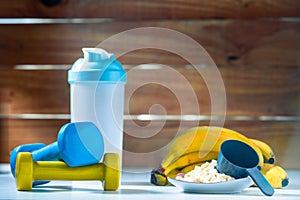 Mixer and whey protein kit with dumbells and bananas after gym