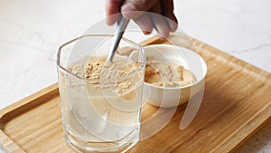 mixing brewers yeast flakes in a glass of water