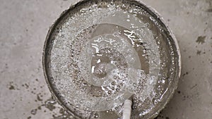 Mixing Building Cement Glue or Mortar with Water in a Bucket Using Construction Mixer with Whisk. Worker mixing plaster