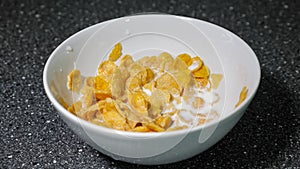Mixing cornflakes and milk in bowl with spoon and eating for breakfast.