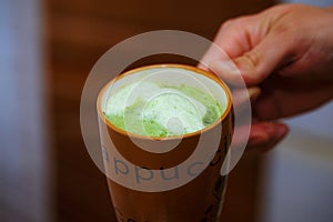 Mixing Green Barley Grass Powder in man hand. Juice for Vitality