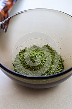 Mixing henna with a wooden spoon in a bowl for hair application of natural color like Indian henna mix