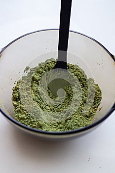 Mixing henna with a wooden spoon in a bowl for hair application of natural color like Indian henna mix