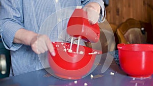 Mixing liquid dough for baking using an electric mixer. Cooking cake. Woman adding ingredients and mixing with electric mixer in t