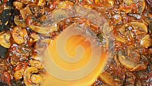 Mixing mushroom sauce with vegetables on the pan close-up