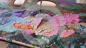 Mixing oil acrylic paints on a palette with palette knife. Bright colored paint close up. Artist mixes paints on the